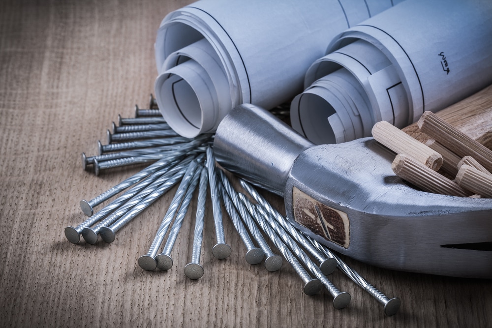 Composition of blueprint rolls claw hammer dowels and construction nails.