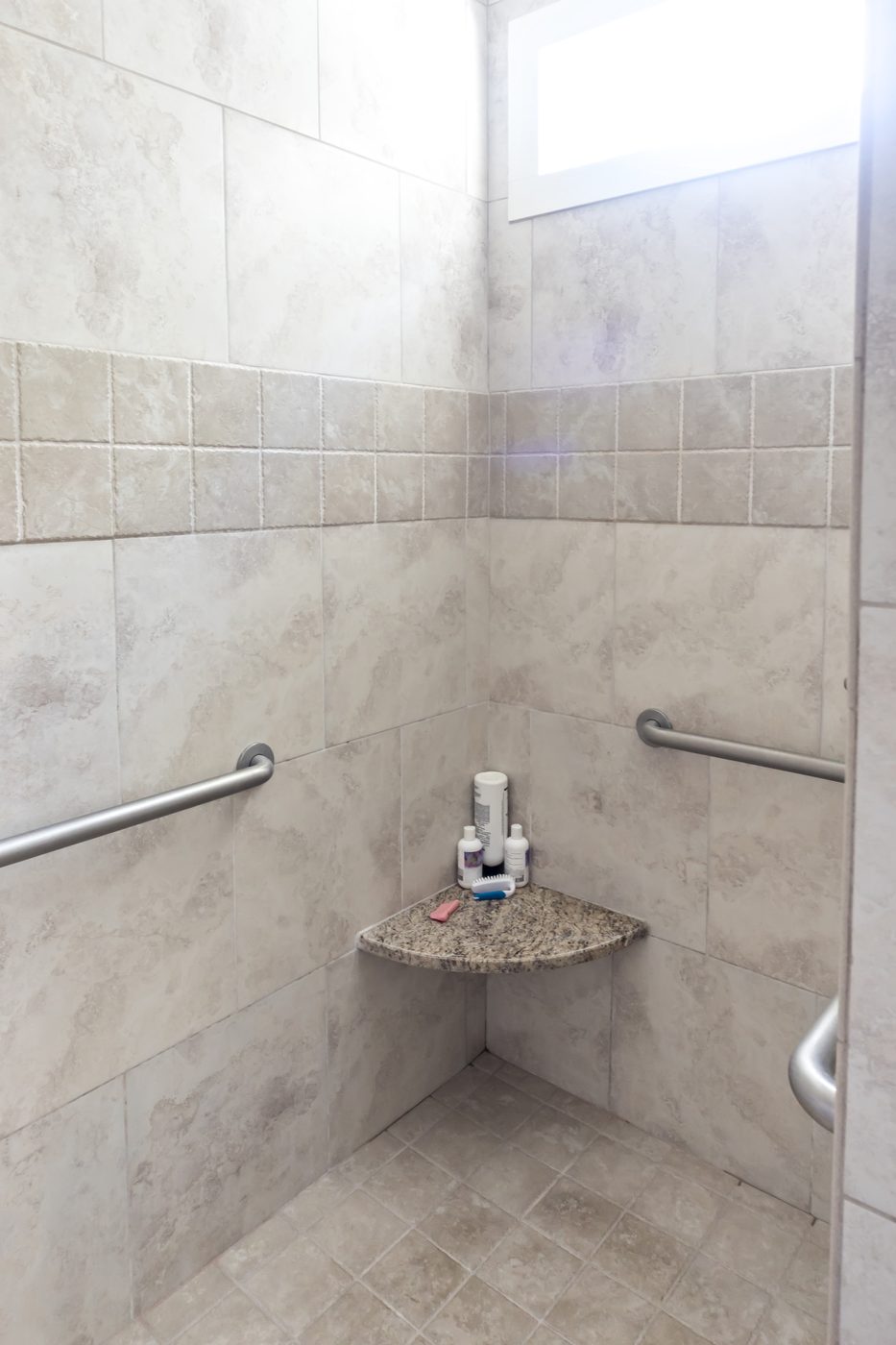 Accessible tiled shower with grab bars and corner seat