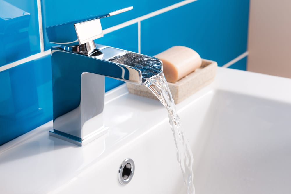 A closeup shot of a modern faucet under the lights at a bathroom - interior concept