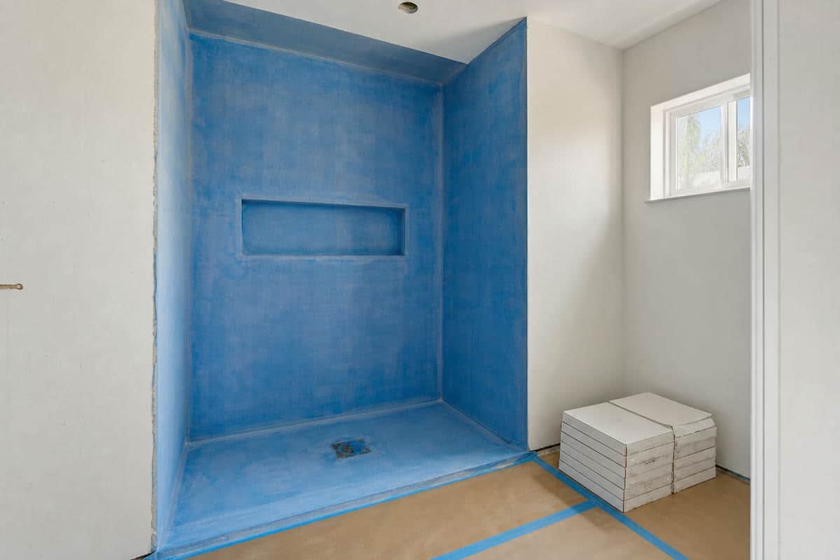 Bathroom remodel in progress with waterproofed shower walls and protected floors