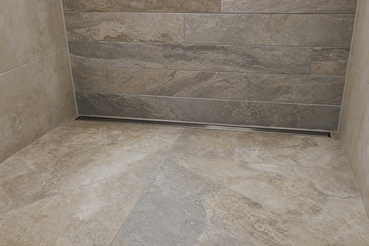 Linear drain along the rear wall of a finished tiled shower