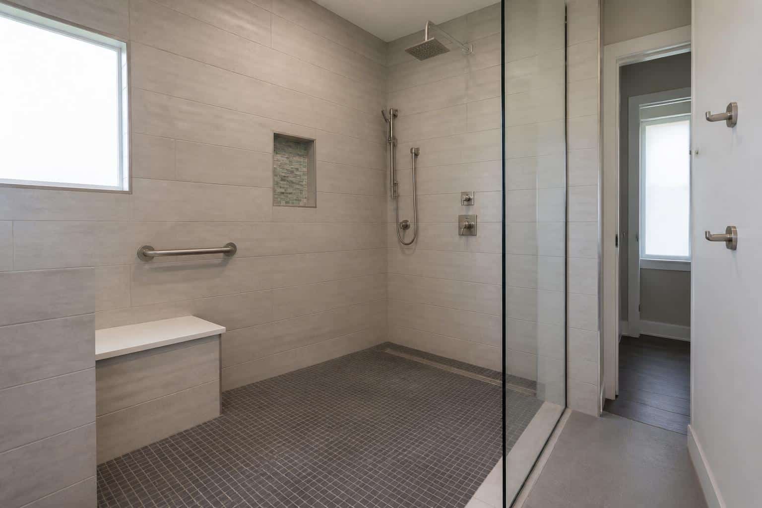 Walk-in shower with wall-mounted folding bench and handheld sprayer on a slide bar